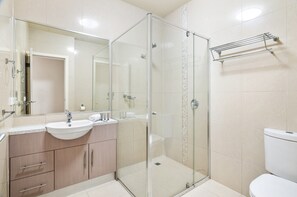 A modern bathroom with a glass shower enclosure, a sink with a mirror, and a towel rack. - Bright 2-bed Flat With Balcony in Kensington (Melbourne)