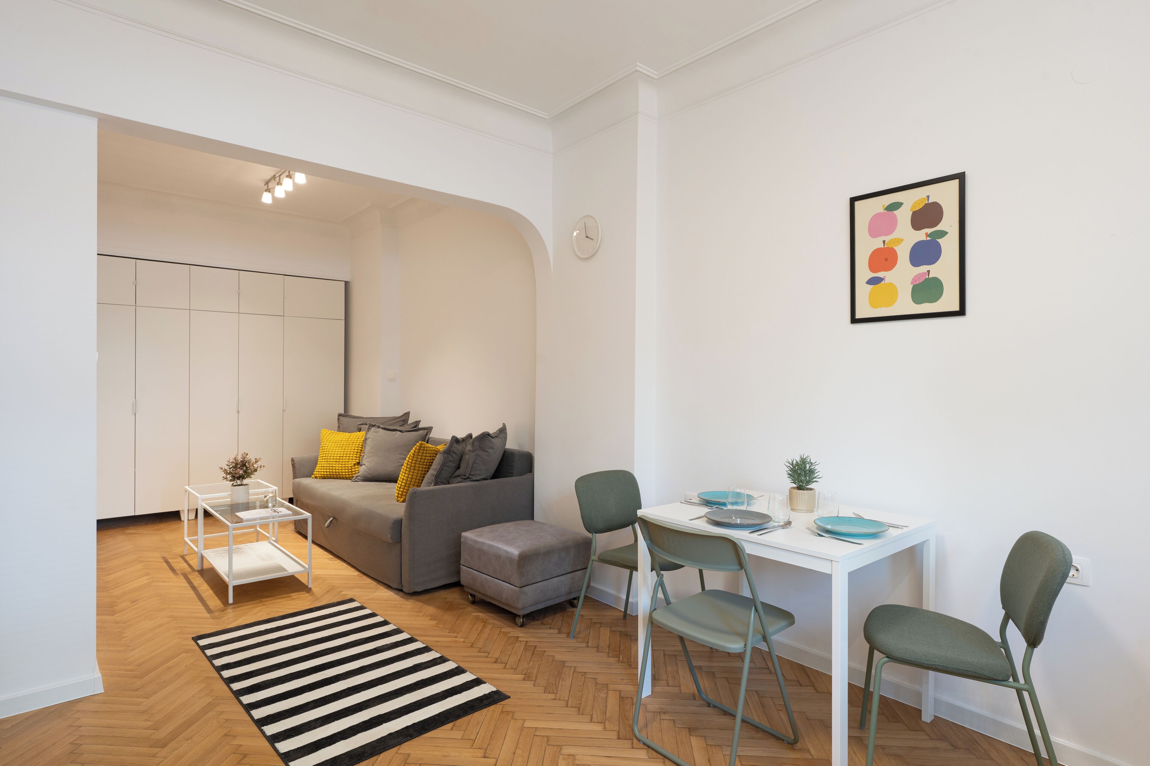 Una sala de estar moderna con un sofá gris, una mesita y un comedor con sillas.