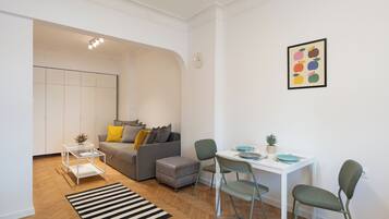 Una sala de estar moderna con un sofá gris, una mesita y un comedor con sillas.