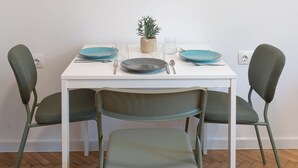 A dining area with a white table, two green chairs, and a framed artwork of colorful apples on the wall. - Starflat Cozy central apartment NDK (Sofia)