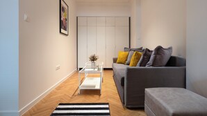 A modern living room with a grey sofa, a white coffee table, and a striped rug. - Starflat Cozy central apartment NDK (Sofia)