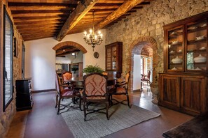 Un coin repas rustique, avec des meubles en bois, des murs en pierre et un lustre.
