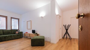 Een moderne woonkamer met een groene bank, een houten kast, een televisie en een kleine tafel met een plant.
