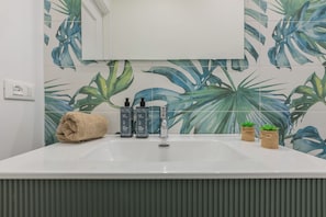 A bathroom with a white sink, two bottles of hair and body wash, a towel, and two small potted plants. - Ormea Cobalto Apartment by Wonderful Italy (Turin)