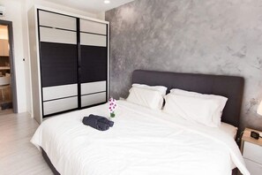A modern bedroom with a large bed, a wardrobe, and a nightstand. - A Modern & Bright Suasana Suites in Johor Bahru (Johor Bahru)