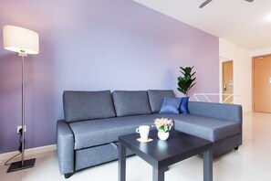 A modern living room with a grey sofa, a coffee table, a floor lamp, and a potted plant. - A Modern & Bright Suasana Suites in Johor Bahru (Johor Bahru)