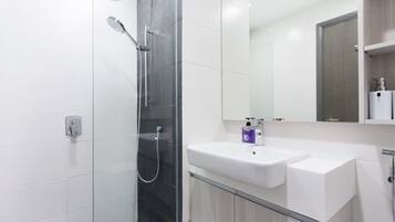 A modern bathroom with a glass-enclosed shower, a white sink, and a mirror above it.