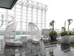 A rooftop lounge with wicker chairs and a pool. - A Modern & Bright Suasana Suites in Johor Bahru (Johor Bahru)