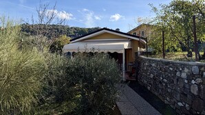 Une maison avec un mur en pierre, une véranda et une vue sur une colline.