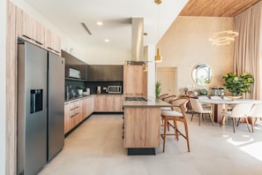 Een moderne keuken met houten kasten, roestvrijstalen apparatuur en een centraal eiland met zitplaatsen.