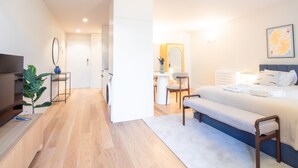 A modern hotel room with a bed, bedside table, and a desk with a chair. There is a bathroom with a mirror and a sink. - Miguel Bombarda 259 by LovelyStay (Porto)
