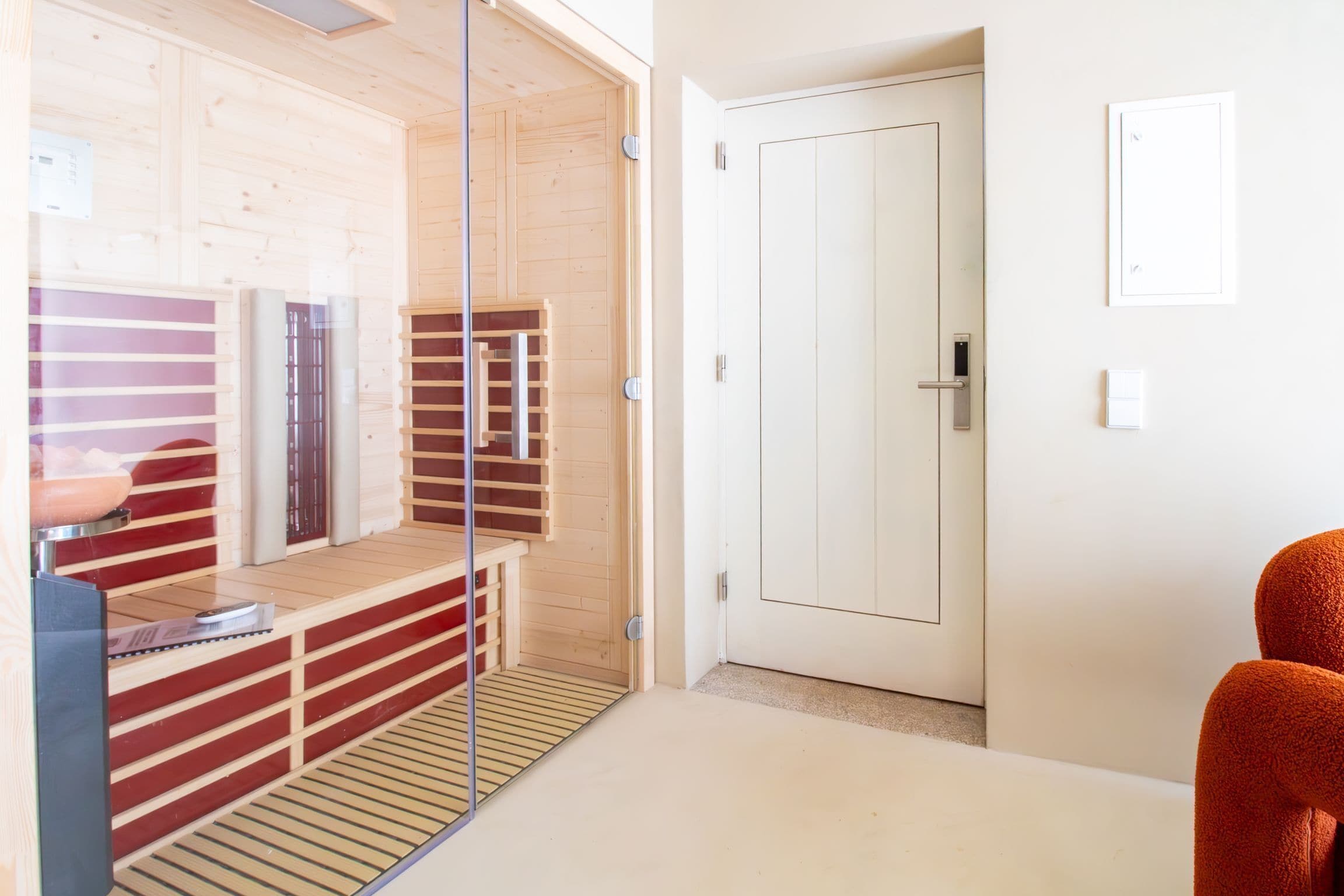 Un sauna avec des murs en bois, une porte en verre et un banc.