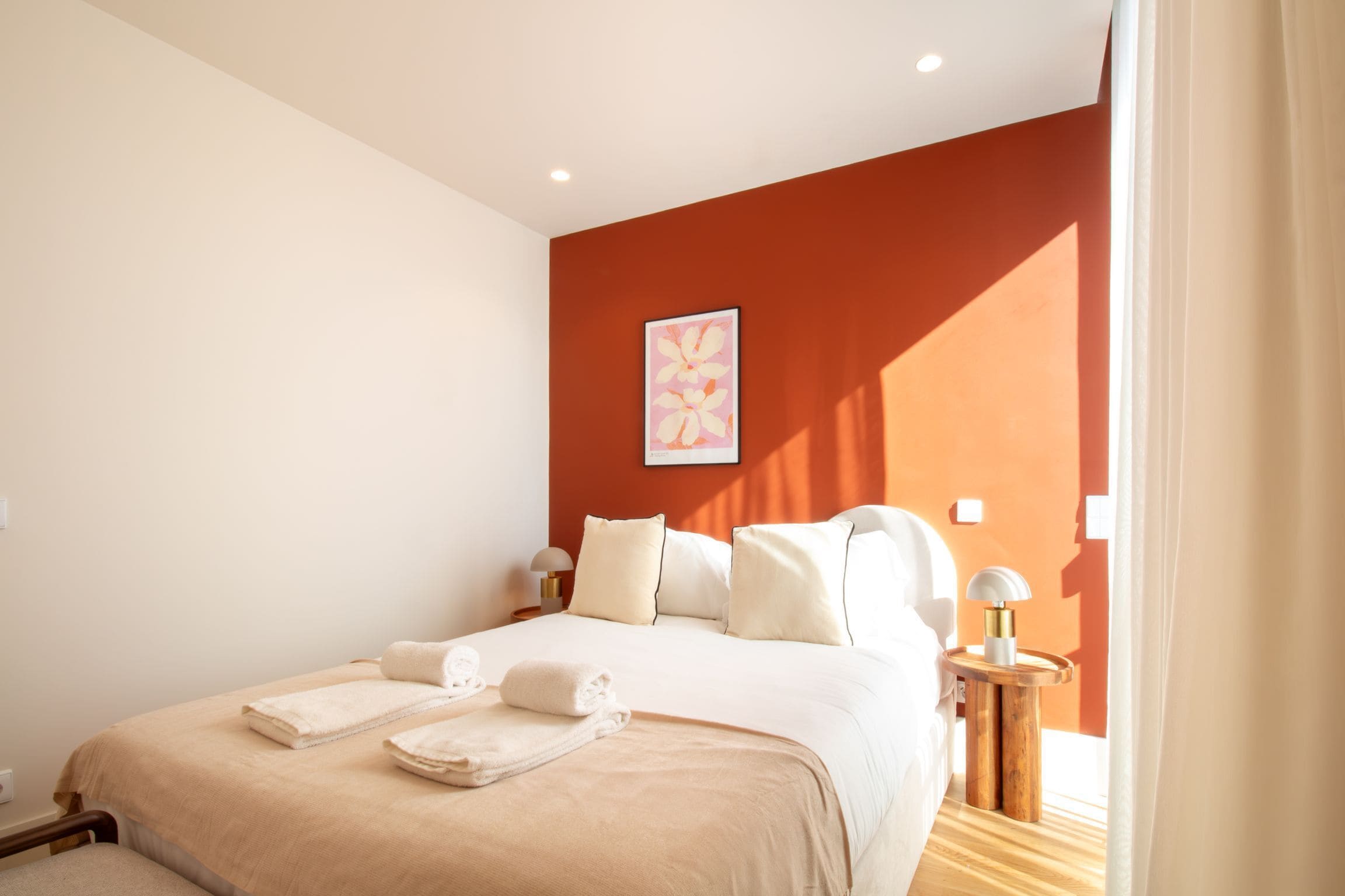 A hotel room with a large bed, two bedside tables, and a wall-mounted artwork.