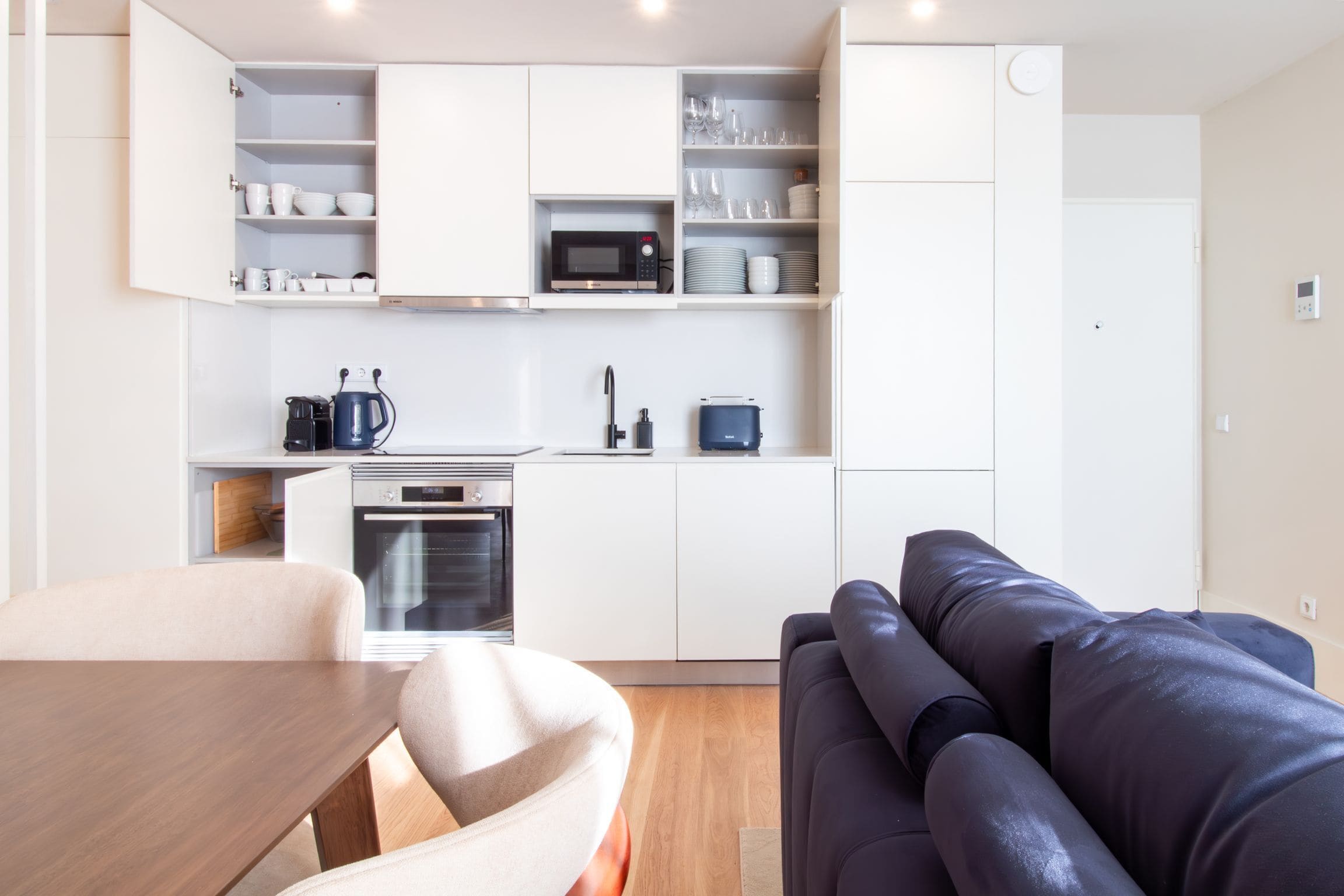 A compact kitchen with white cabinets, a microwave, and a coffee machine.