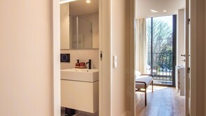 A modern bathroom with a large mirror, white cabinetry, and a view of a balcony. - Miguel Bombarda 259 by LovelyStay (Porto)