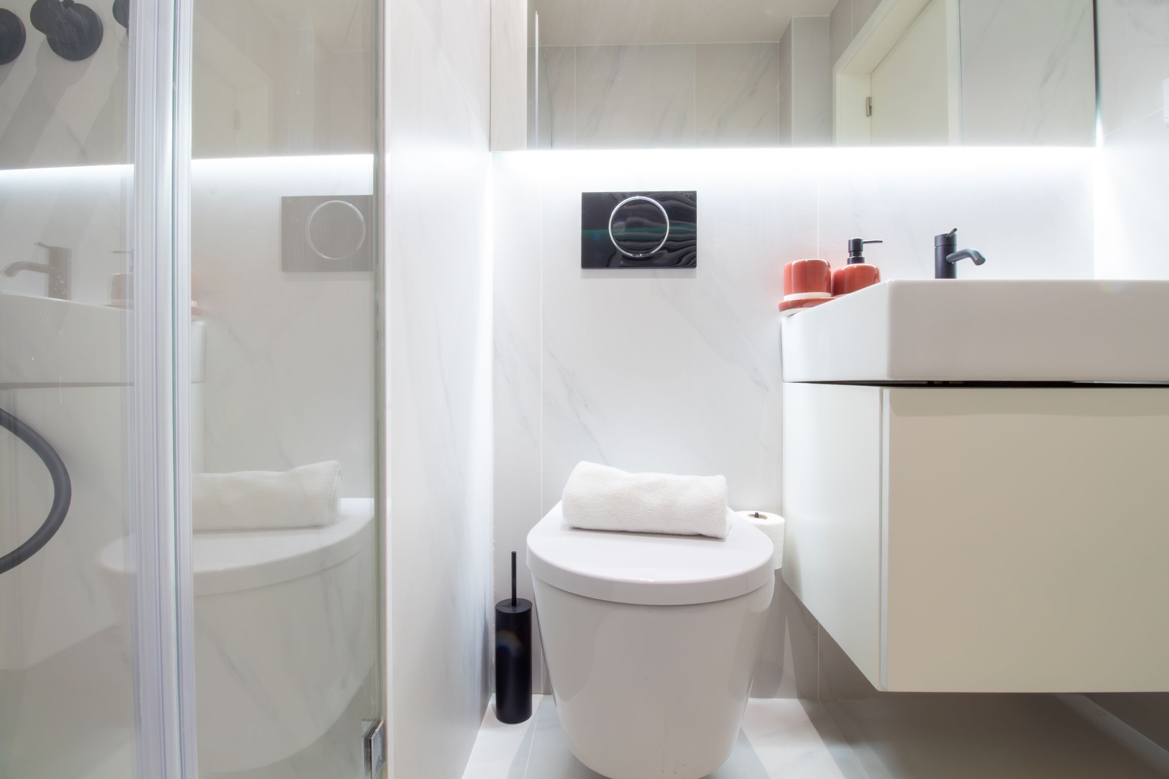 Une salle de bain moderne équipée de toilettes, d’un lavabo et d’une douche à parois en verre.