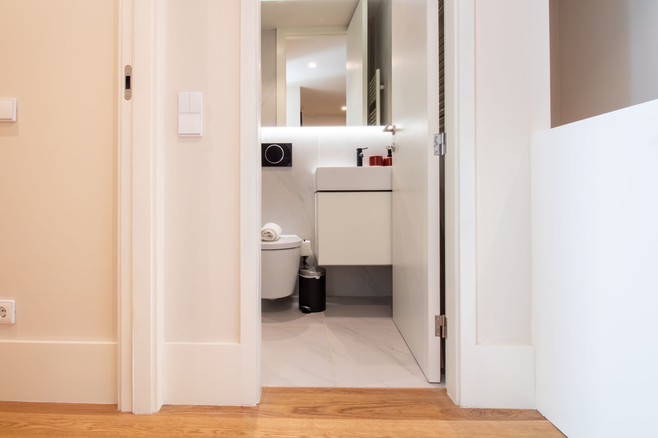A modern bathroom with a toilet, sink, and mirror.