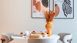 A dining table with breakfast items, a vase with dried plants, and abstract art on the wall. - Miguel Bombarda 259 by LovelyStay (Porto)