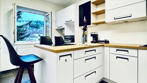 Une cuisine moderne avec des armoires blanches, un plan de travail en bois et une chaise noire.