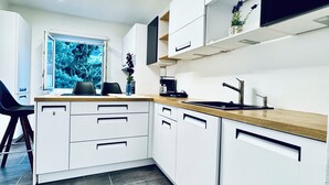 Une cuisine moderne avec des armoires blanches, un plan de travail en bois et une grande fenêtre.