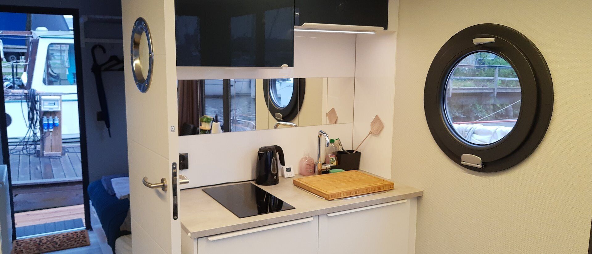 Et kompakt tekøkken med vask, lille bordplade, kaffemaskine og et vindue med udsigt.