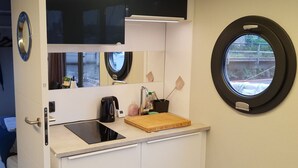 Eine kleine Küchenzeile mit Spüle, einer Arbeitsfläche, einer Kaffeemaschine und einem Fenster mit Ausblick.