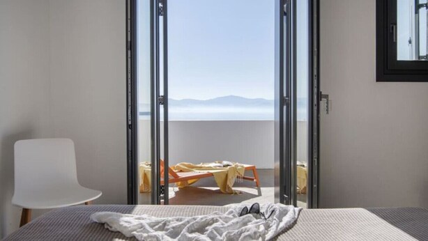 Un dormitorio con cama, una silla y un balcón con mesa y sillas.