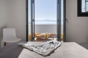 A bedroom with a bed, a chair, and a balcony with a table and chairs. - Villa Ela - Family gathering (Santa Maria)