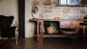 A rustic wooden table with a woven basket and a potted plant, set against a stone wall with a hanging lamp. - La Pagliera  (Agrigento)