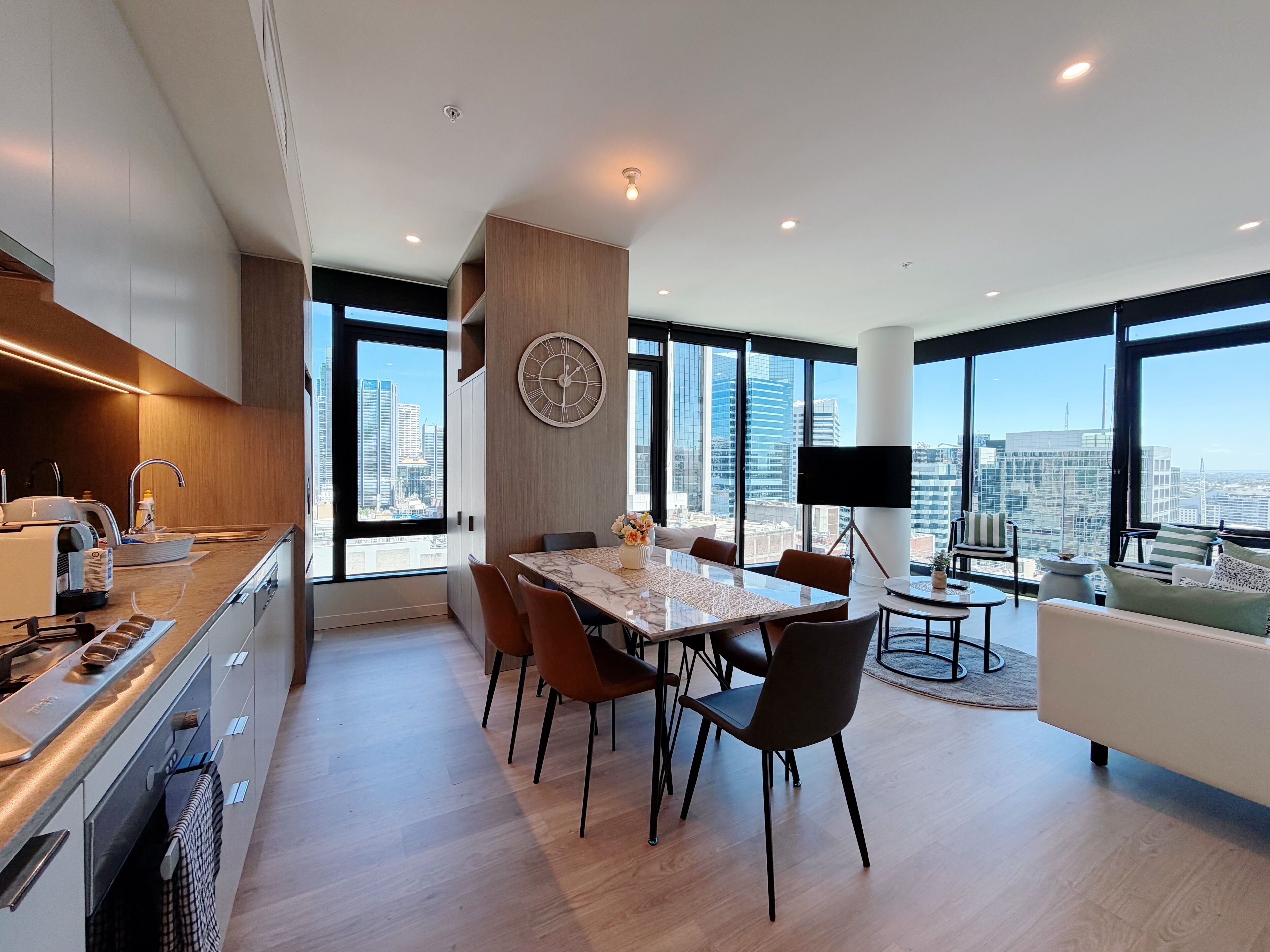 A modern kitchen with a dining area, large windows, and a city view.