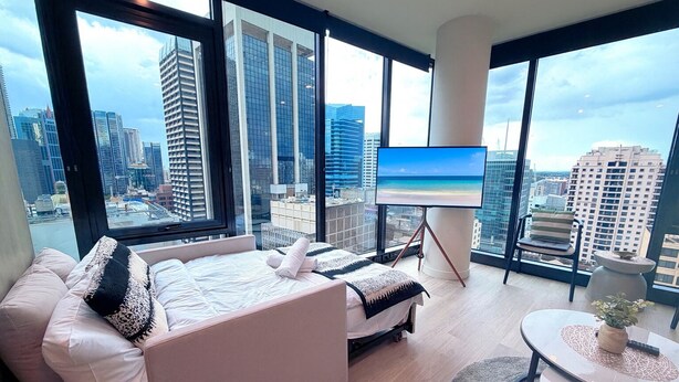 Ein modernes Hotelzimmer mit einem großen Bett, einem Fernseher und einem Balkon mit Blick auf die Stadt.