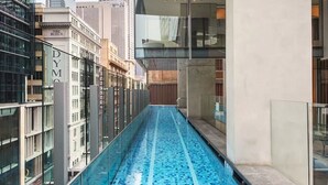 Ein schmaler, überdachter Pool mit Glaswänden, umgeben von modernen Gebäuden.