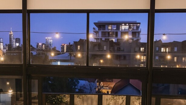 A dining area with a table set for four, surrounded by chairs, and a view of a cityscape through large windows. - Fun for Families: Location, Cinema, Games, Wifi (Perth)