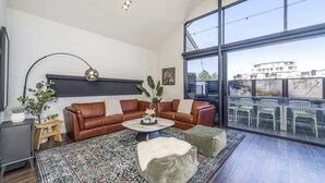 A modern living room with a large window, leather sofas, a coffee table, and a view of the city. - Fun for Families: Location, Cinema, Games, Wifi (Perth)