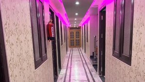 A hallway with patterned wallpaper, black and white striped flooring, and doors with mesh windows. - Hotel shri ram krishna mahal (Ayodhya)