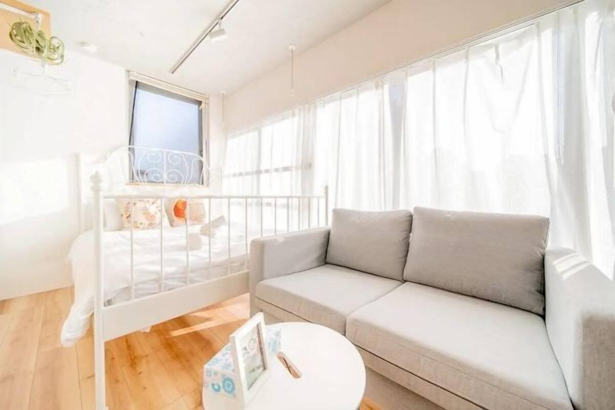 A bright living room with a white sofa, a small round table, and a window with curtains.
