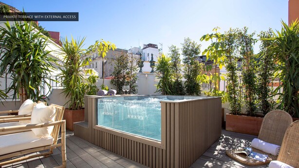 Une terrasse privée avec un jacuzzi extérieur accessible depuis l’extérieur, une terrasse en bois et un espace salon extérieur agrémenté de coussins.