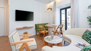 Un salon moderne avec un téléviseur à écran plat, une table à manger ronde et un canapé.