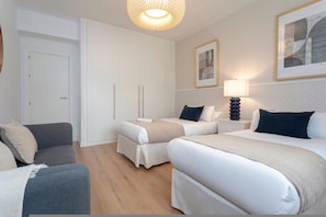 A hotel room with two beds, a sofa, a wardrobe, and a bedside table with a lamp. - Exclusive apt 3rooms in Granada Martinez Campos II (Granada)