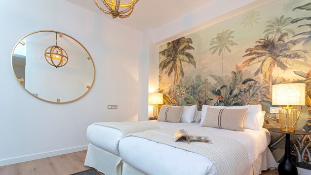 A bedroom with a large bed, a round mirror, a tropical mural, and two bedside lamps. - Exclusive apt 3rooms in Granada Martinez Campos II (Granada)