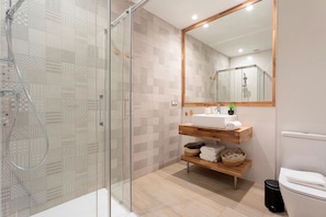 A modern bathroom with a glass shower enclosure, a wooden vanity with a mirror, and a toilet. - Exclusive apt 3rooms in Granada Martinez Campos II (Granada)