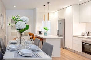 A modern kitchen with white cabinetry, a central island, and a dining area with a table set for four. - Exclusive apt 3rooms in Granada Martinez Campos II (Granada)