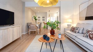 A modern living room with a flat-screen TV, a sofa, a coffee table with decorative items, and a dining area in the background. - Exclusive apt 3rooms in Granada Martinez Campos II (Granada)