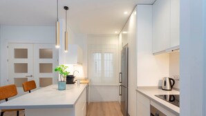 A modern kitchen with white cabinetry, a central island, and a stainless steel refrigerator. - Exclusive apt 3rooms in Granada Martinez Campos II (Granada)