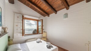 Ett sovrum med en säng, ett fönster med utsikt, en stol och ett litet bord med en lampa.