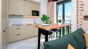 Eine moderne Küche mit Essbereich, einem großen Fenster und Blick sowie einem grünen Sofa.