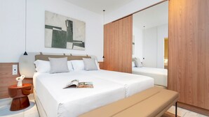 Een moderne slaapkamer met een groot bed, een bankje, een houten garderobe en een schilderij aan de muur.