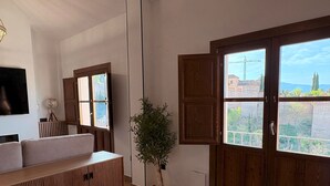 A modern living room with a sofa, a wooden cabinet, and a large window with a view of the city. - Lovely Loft With Views in Granada Mirador de Aixa (Granada)