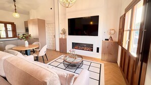 A modern living room with a sofa, a coffee table, a TV, a fireplace, and a dining area. - Lovely Loft With Views in Granada Mirador de Aixa (Granada)