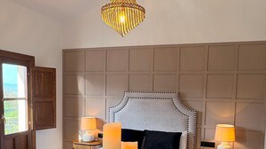 A bedroom with a large bed, two bedside tables with lamps, a hanging light fixture, and a wooden door. - Lovely Loft With Views in Granada Mirador de Aixa (Granada)